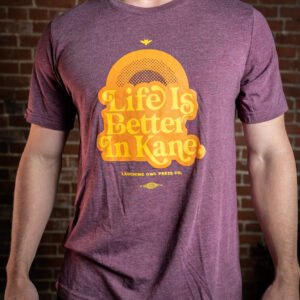 Man wearing maroon t-shirt that reads life is better in kane in yellow text