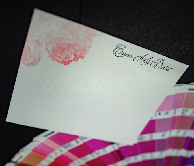 A letterpress printed flat card laying on a Pantone swatch book